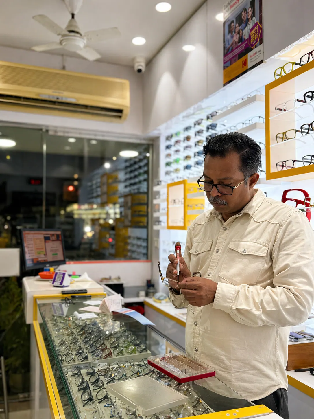 Jignesh Vora inspecting a spectacle frame before fitting at Ami Optics