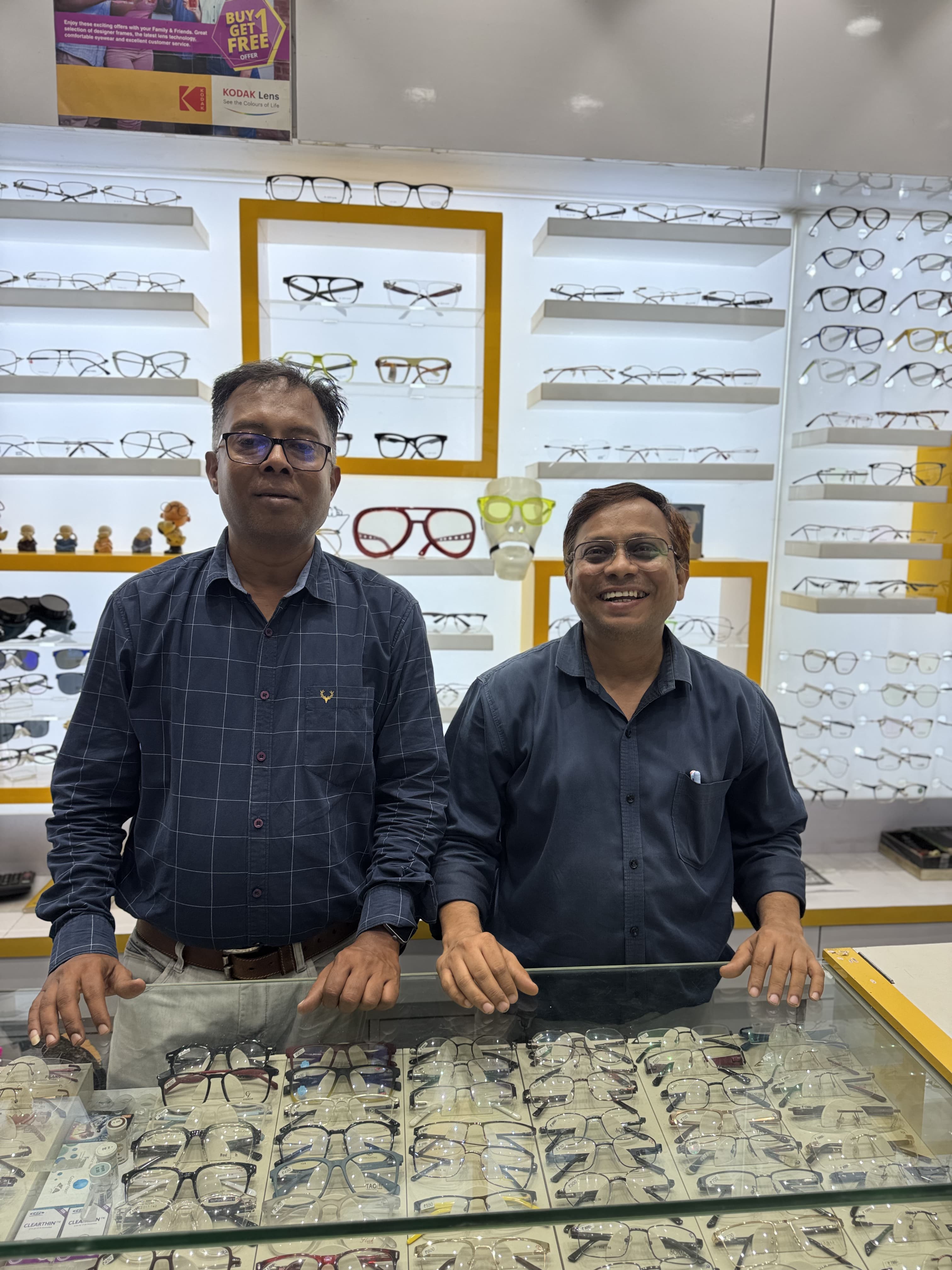 Jignesh and Jatin Vora today, smiling behind the counter at Ami Optics